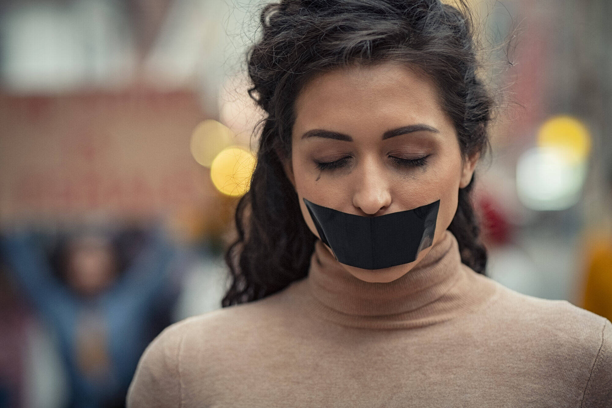 Une femme, les yeux fermés, un ruban sur la bouche Une femme, les yeux fermés, un ruban sur la bouche