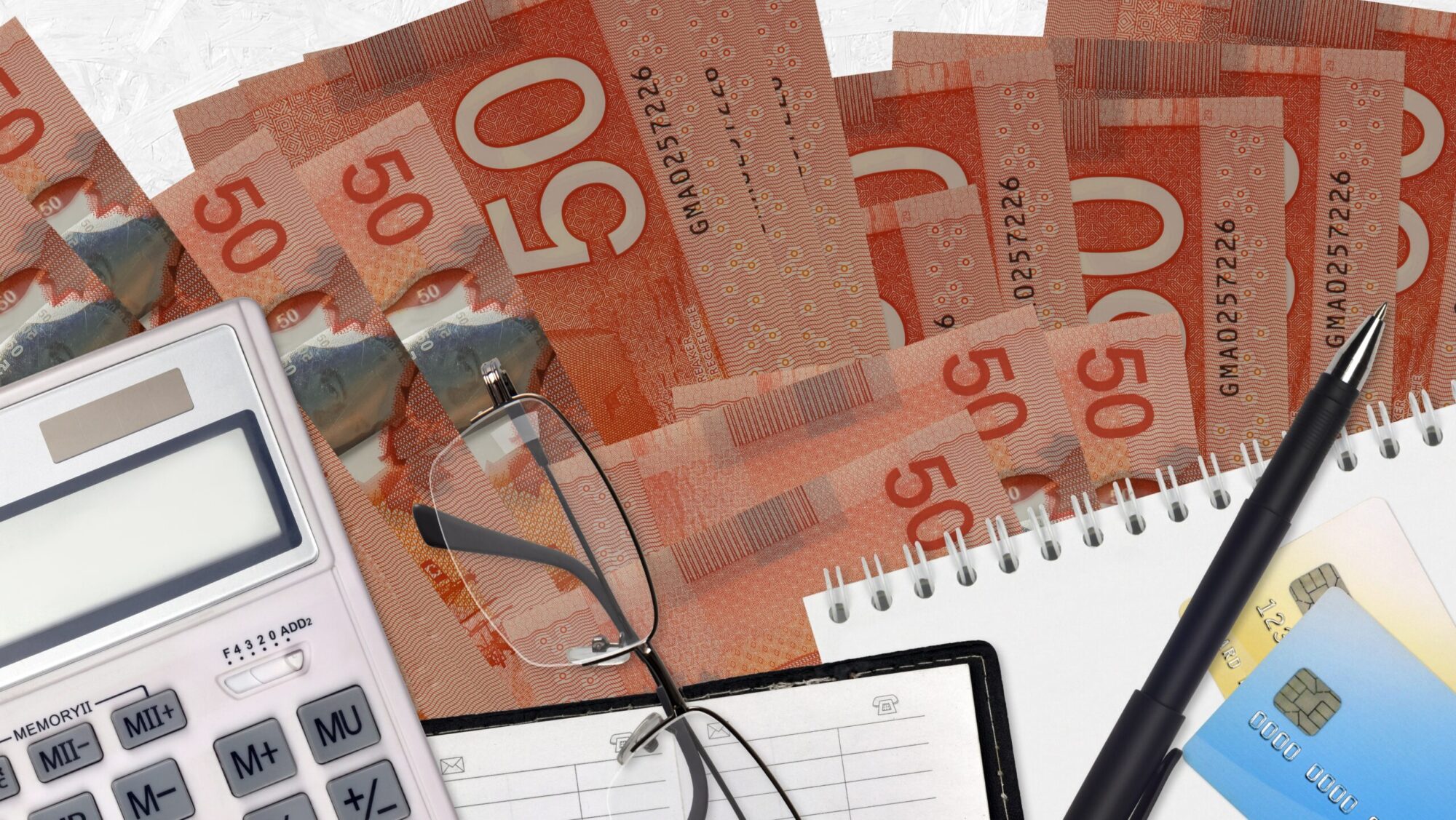 50 Canadian dollars bills and calculator with glasses and pen. Tax payment concept or investment solutions. Financial planning or accountant paperwork