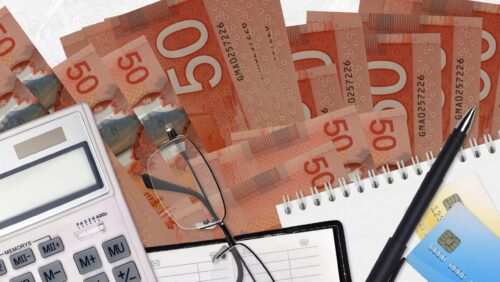 50 Canadian dollars bills and calculator with glasses and pen. Tax payment concept or investment solutions. Financial planning or accountant paperwork