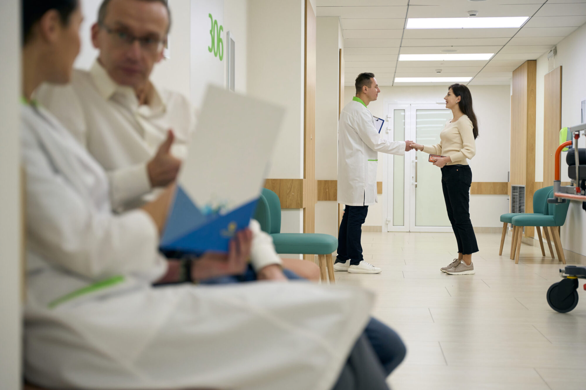 Background, handshake between a doctor and patient in hospital corridor