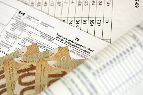 Canadian T4 tax form Statement of remuneration paid lies on table with canadian money bills