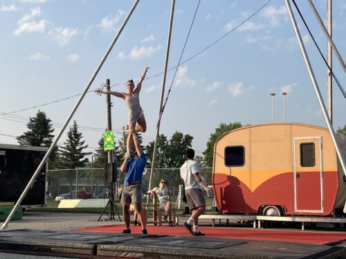 Des acrobates réalisent une performance sur une scène extérieure dans un environnement urbain pendant la saison estivale.