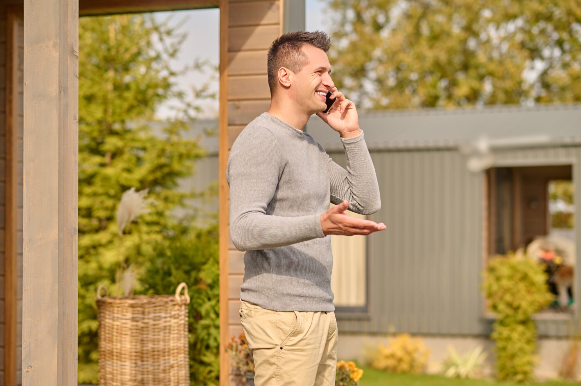 Un homme parle au téléphone à l'extérieur d'une maison en automne.