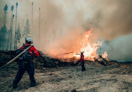 Deux pompiers de la SOPFEU combattent un incendie de forêt.
