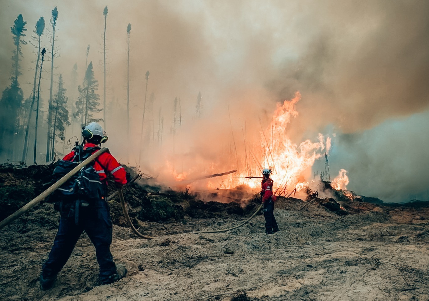 Deux pompiers de la SOPFEU combattent un incendie de forêt.