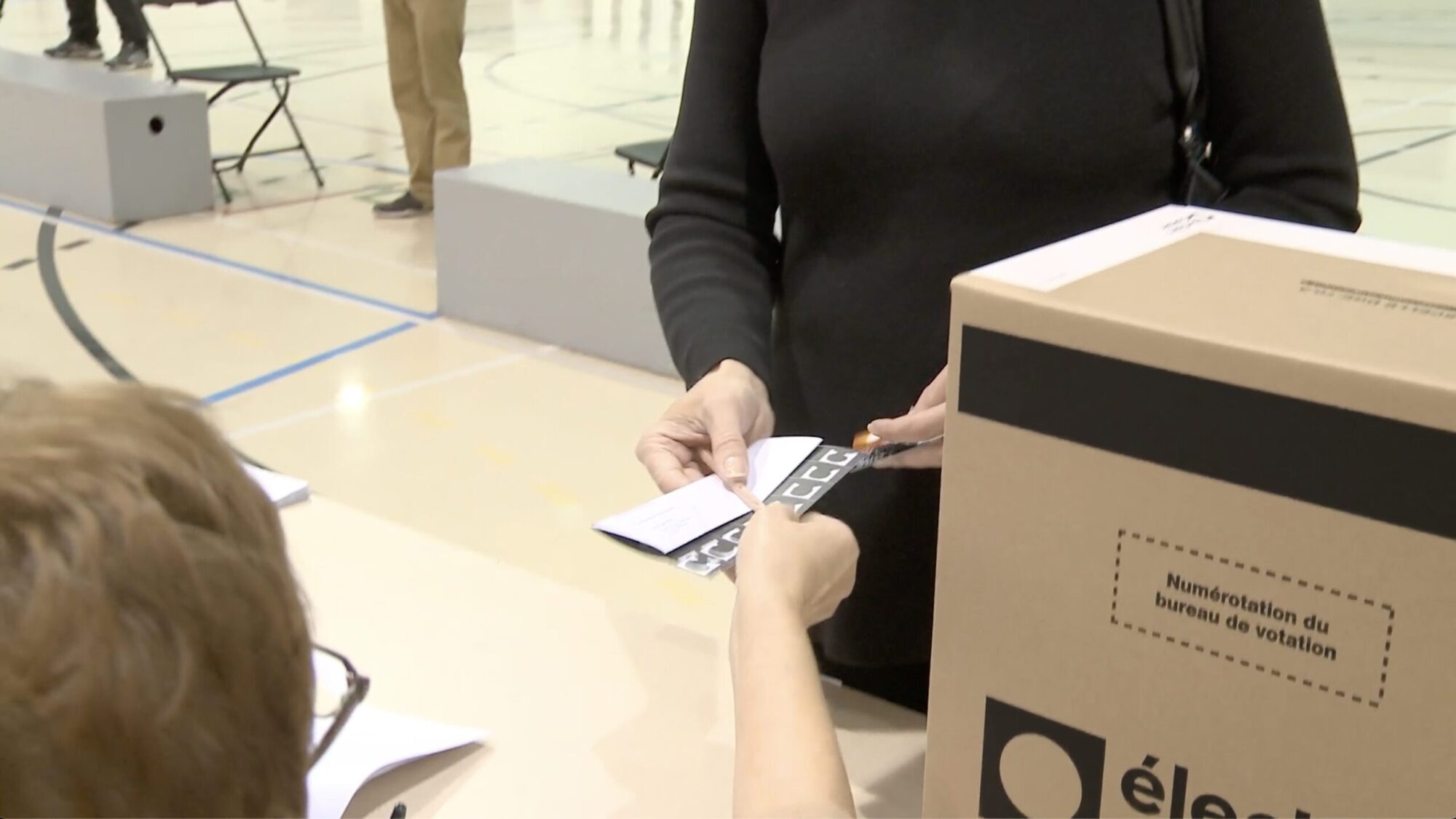 Une personne reçoit son bulletin de vote dans un bureau de scrutin.