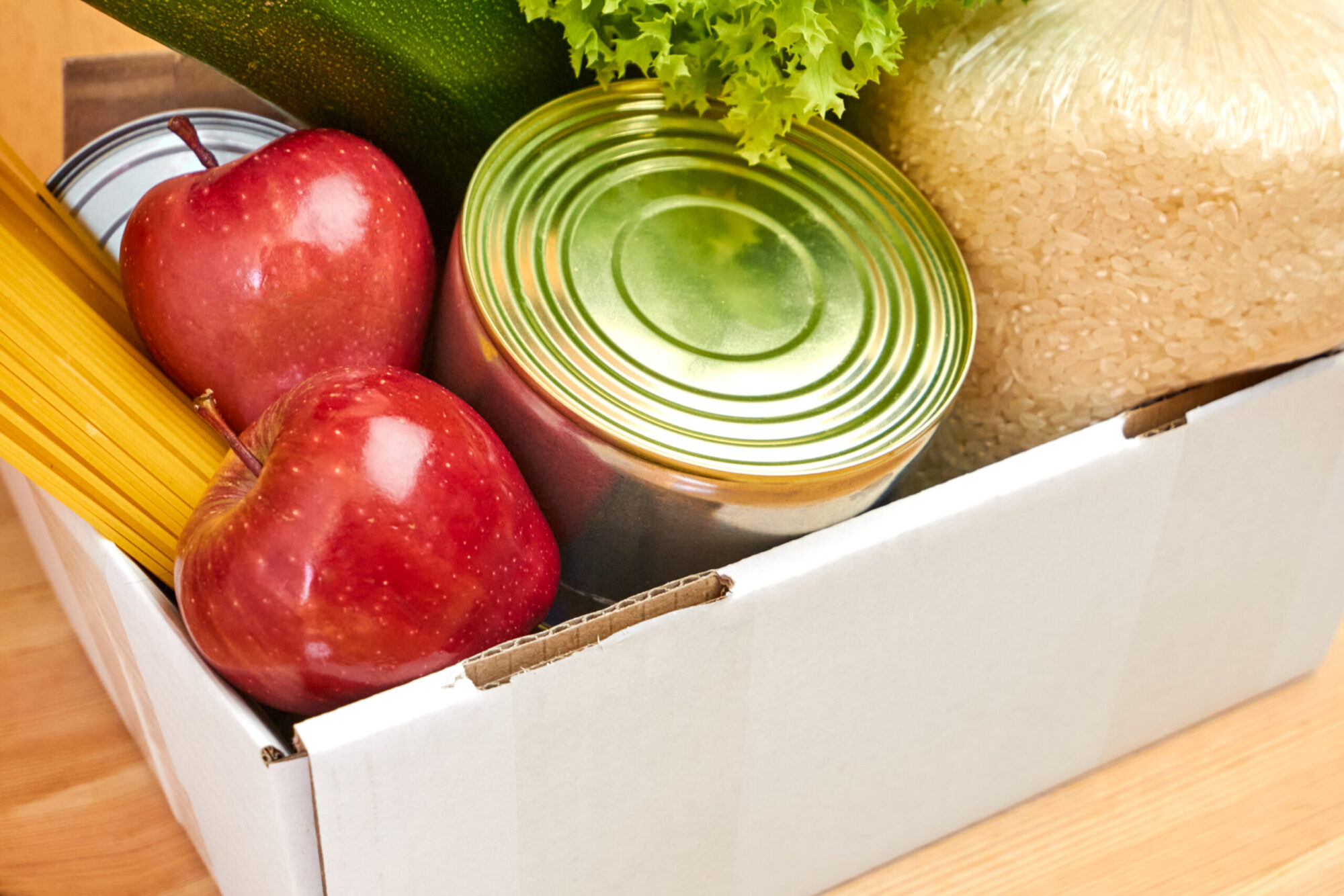 Une boîte en carton contenant des fruits, des légumes et des boîtes de conserve.