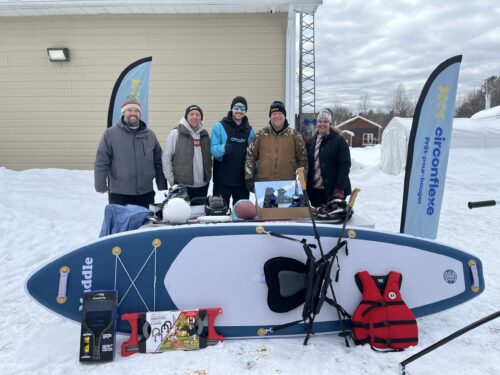 Cinq personnes pose pour une photo devant des équipements sportif.
