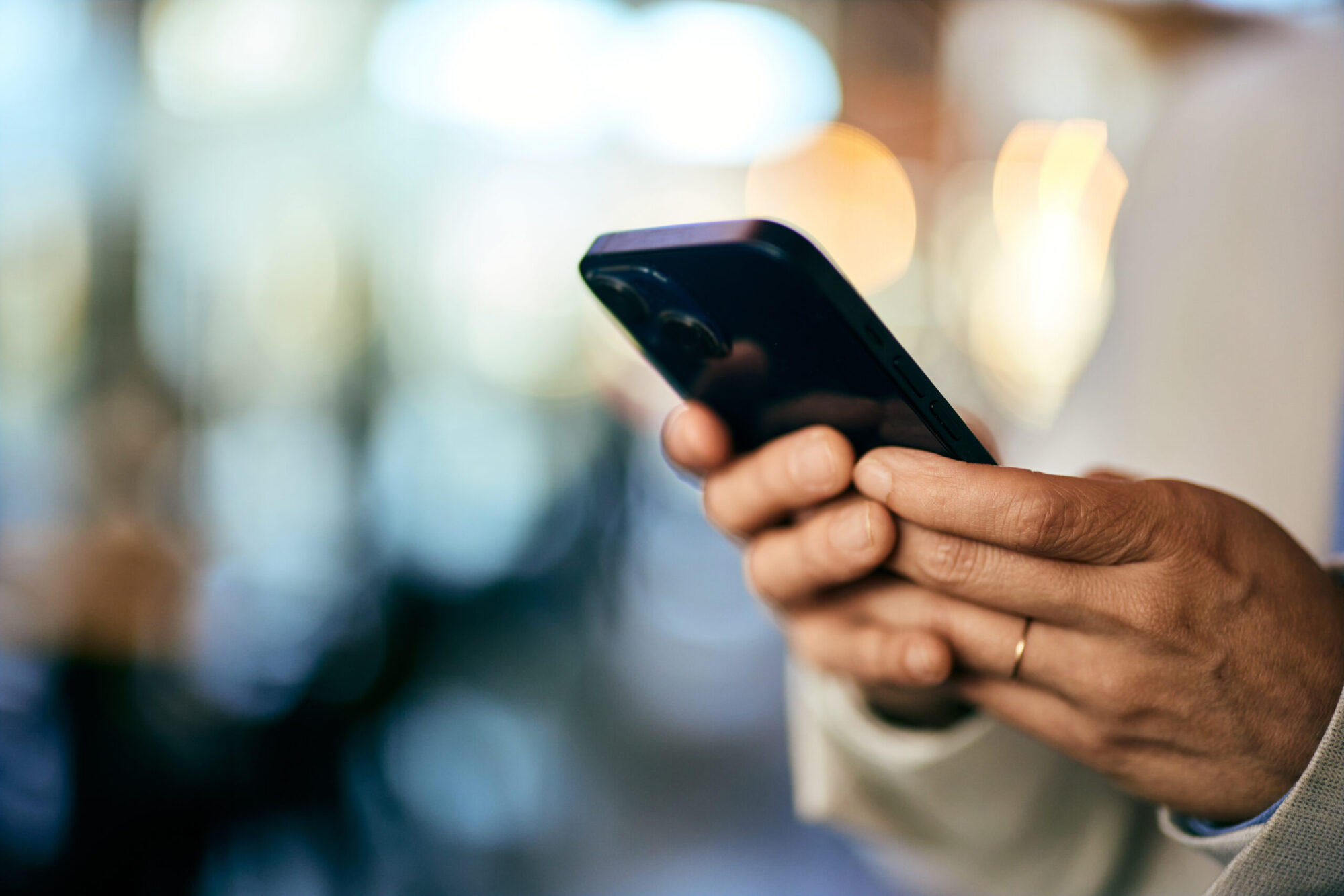 Une femme tient dans ses mains un téléphone cellulaire noir.