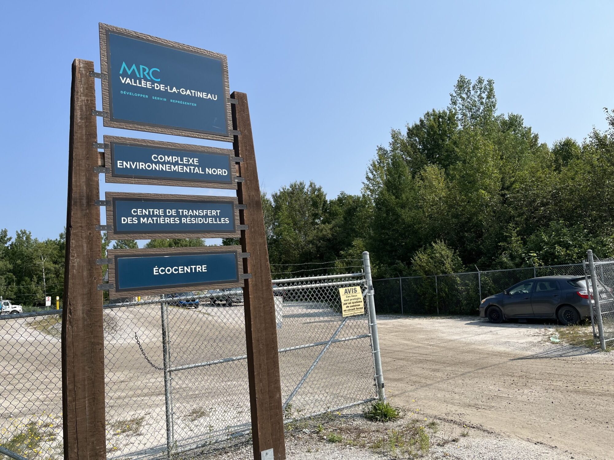 Une pancarte près d'un clôture indique l'emplacement d'un complexe environnemental en été.