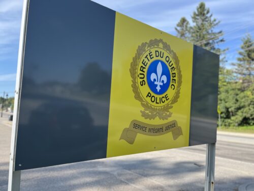 Une pancarte avec le logo de la Sûreté du Québec indique la présence d'un poste policier en bordure d'une route en été.