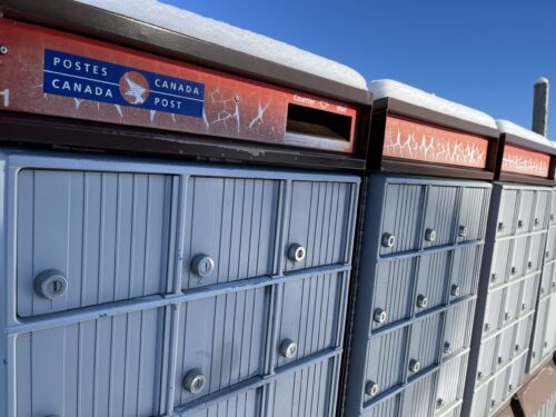 Gros plan sur des boîtes postales communautaires dans un village du Québec en hiver.