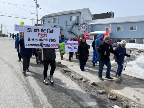 Des manifestants avec des pancartes marchent dans une rue d'une ville au printemps.