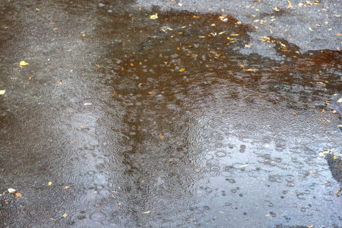 Rain water drops falling to the city street floor in autumn rainy day
