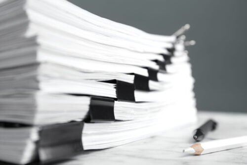 Stack of documents with binder clips on marble table, closeup