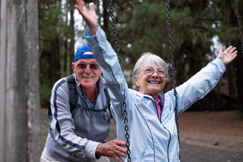 Happy senior woman sitting on swing in the forest enjoying relax