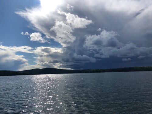 photo couleur lac Blue Sea, avec ciel nuageux, soleil et montagne au loin