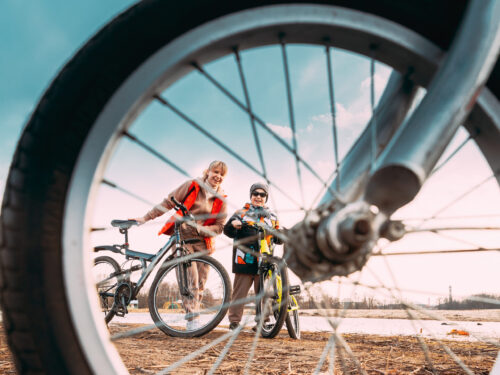 Femme et enfant devant vélo sur piste cyclable, prise de vue à travers rayon de roue de vélo