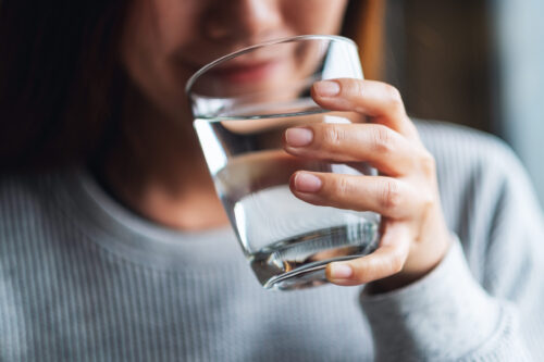 Une femme boit un verre d'eau.