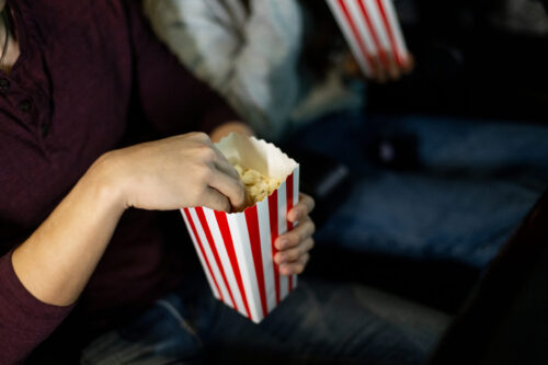 Une personne mange du maïs soufflé en regardant un film.