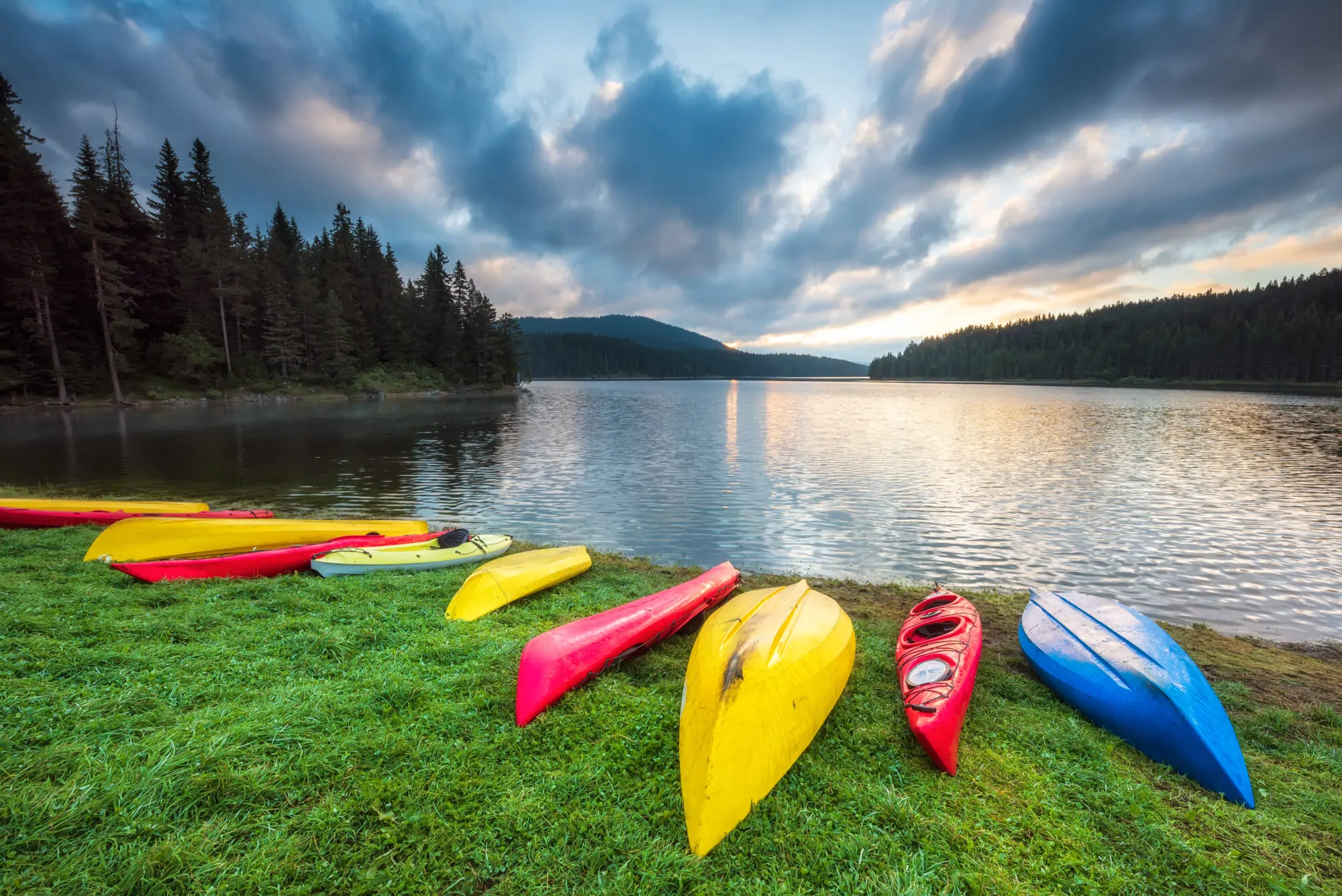 Kayaks colorés étendues sur la berge d'un lac sur lequel du kayak coloré pourrait être fait