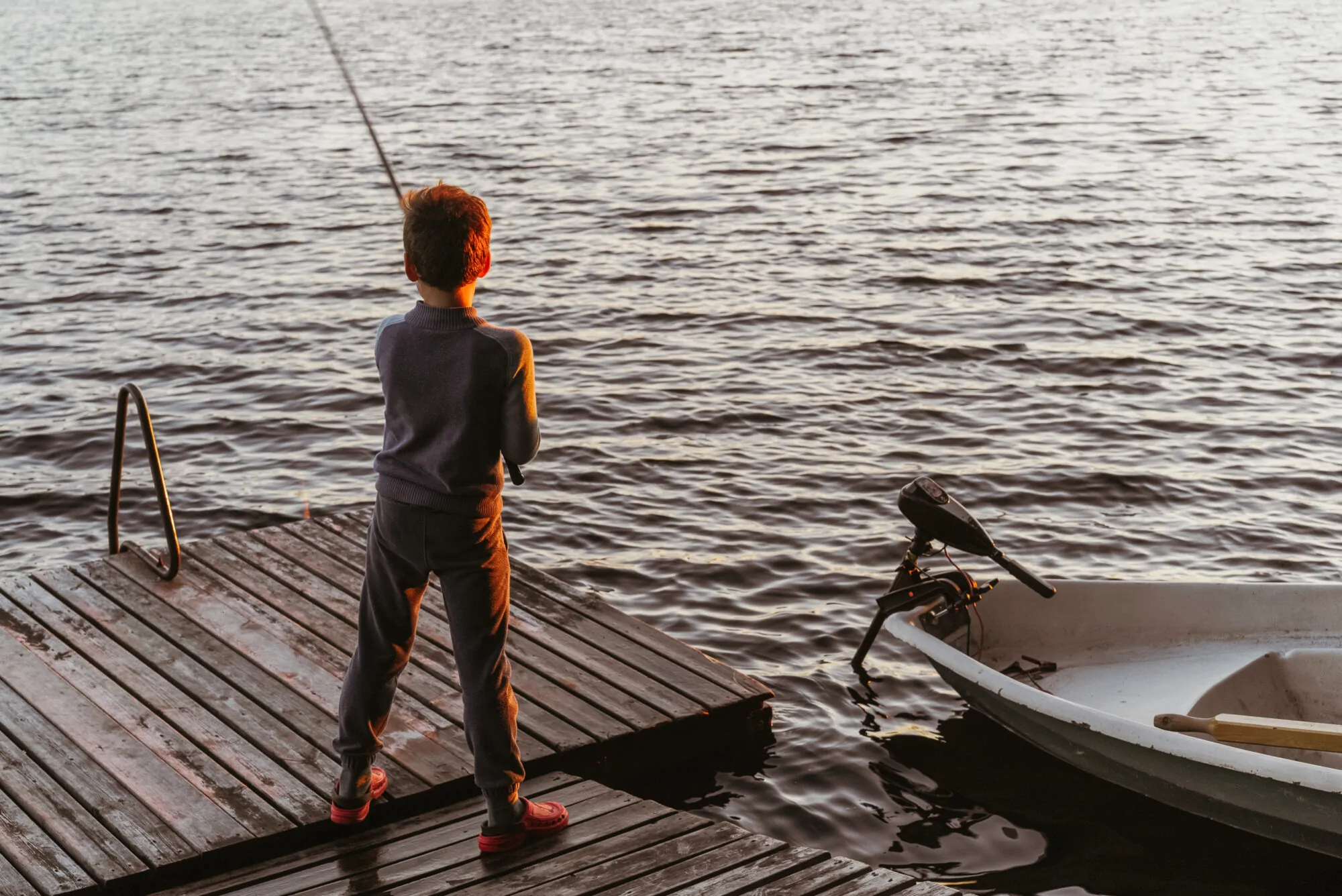 Ti gars qui pêche le poisson sur un quai dans un lac Ti gars qui pêche le poisson sur un quai dans un lac