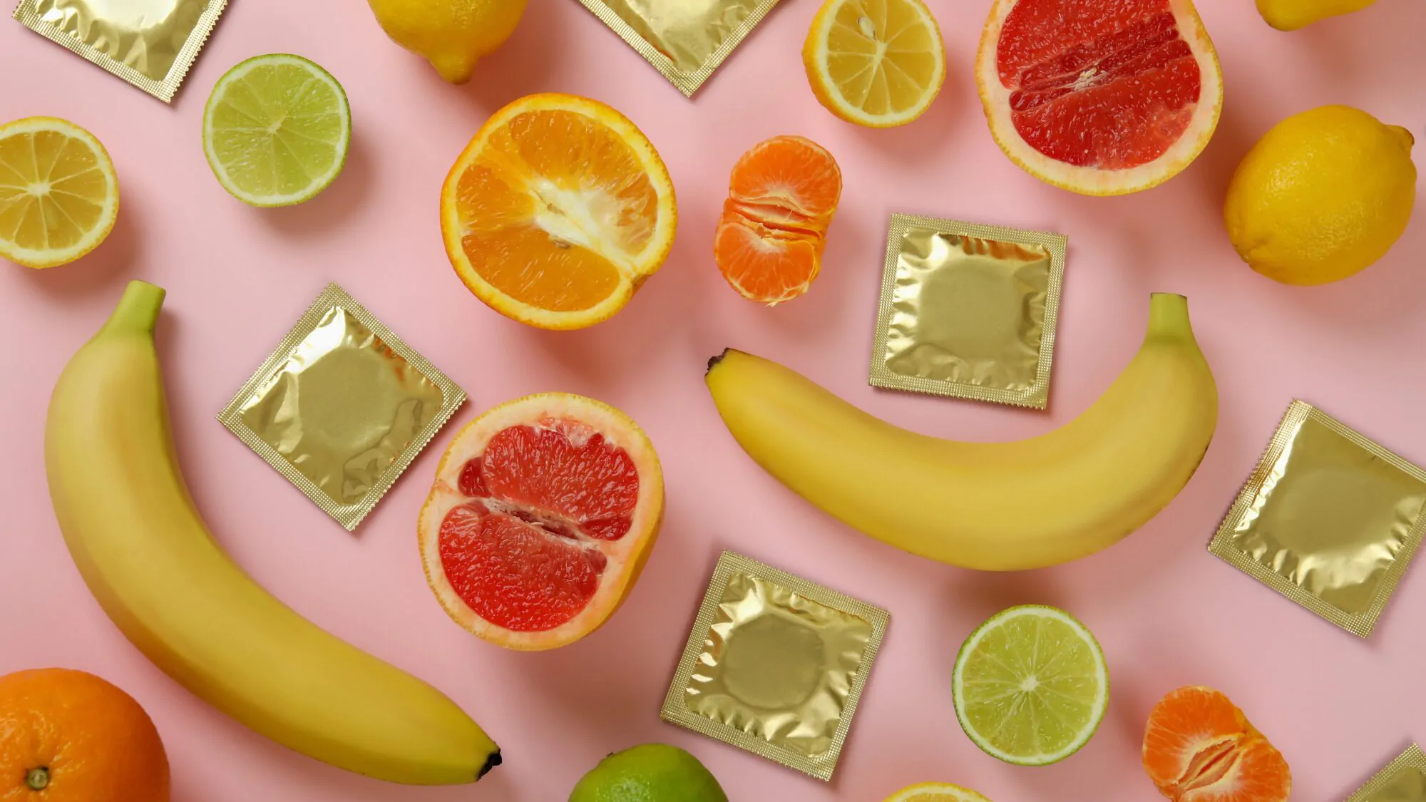 Sex concept with fruits and condoms on pink background