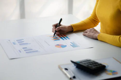 A female financier is reviewing company financial documents, mon