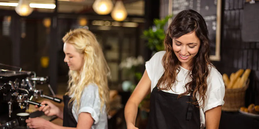 Pretty waitresses behind the counter working at the coffee shop