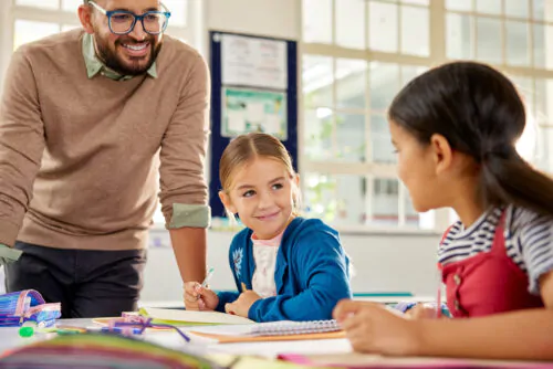 Satisfied little girl in classroom with teacher