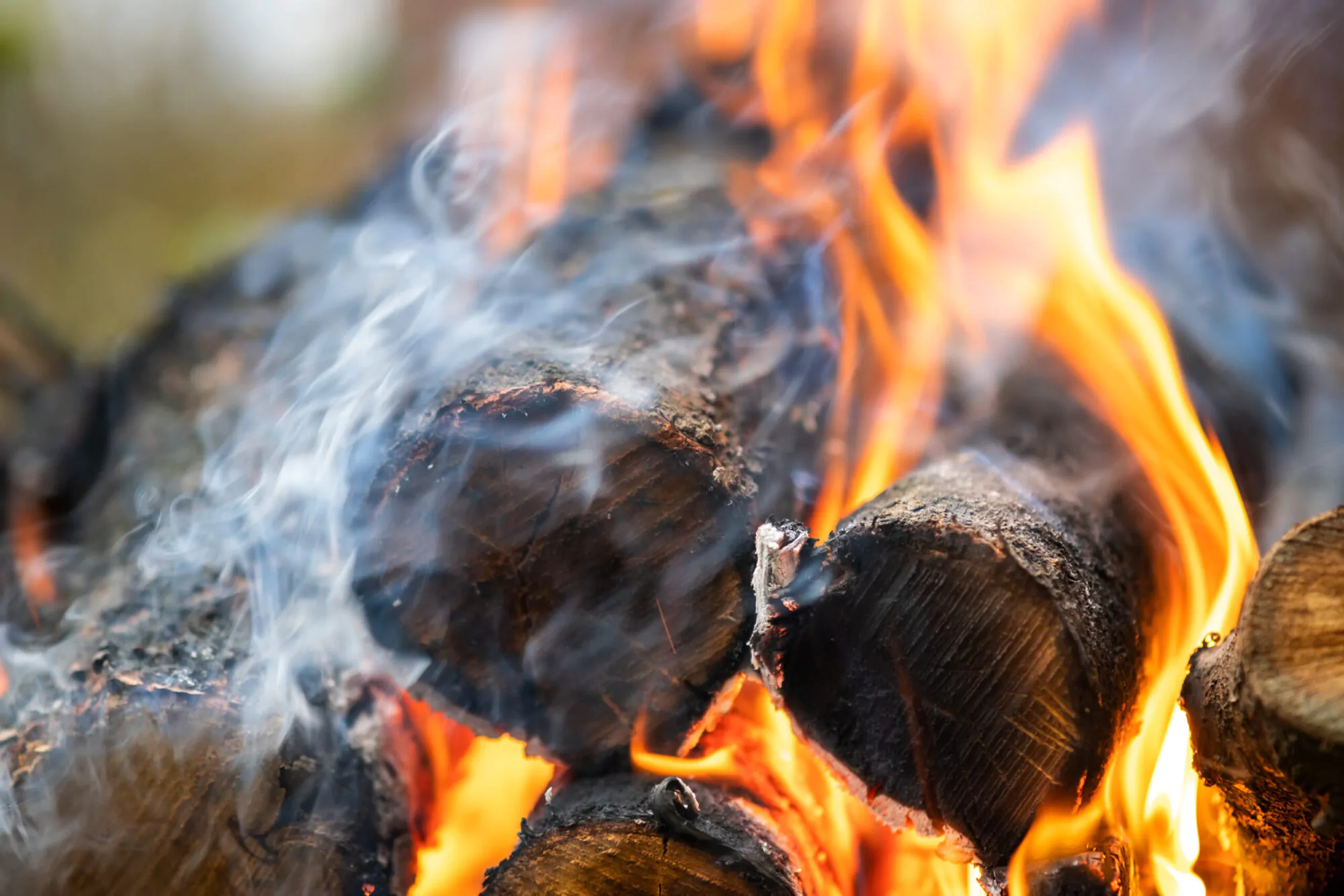 Close up of brightly burning wooden logs with yellow hot flames
