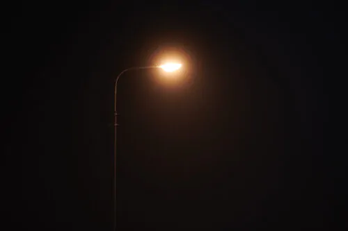 One night lamppost shines with faint mysterious yellow light through evening fog, copy space