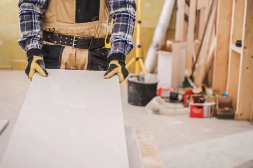 Male Contractor Holding Piece Of Drywall Material.