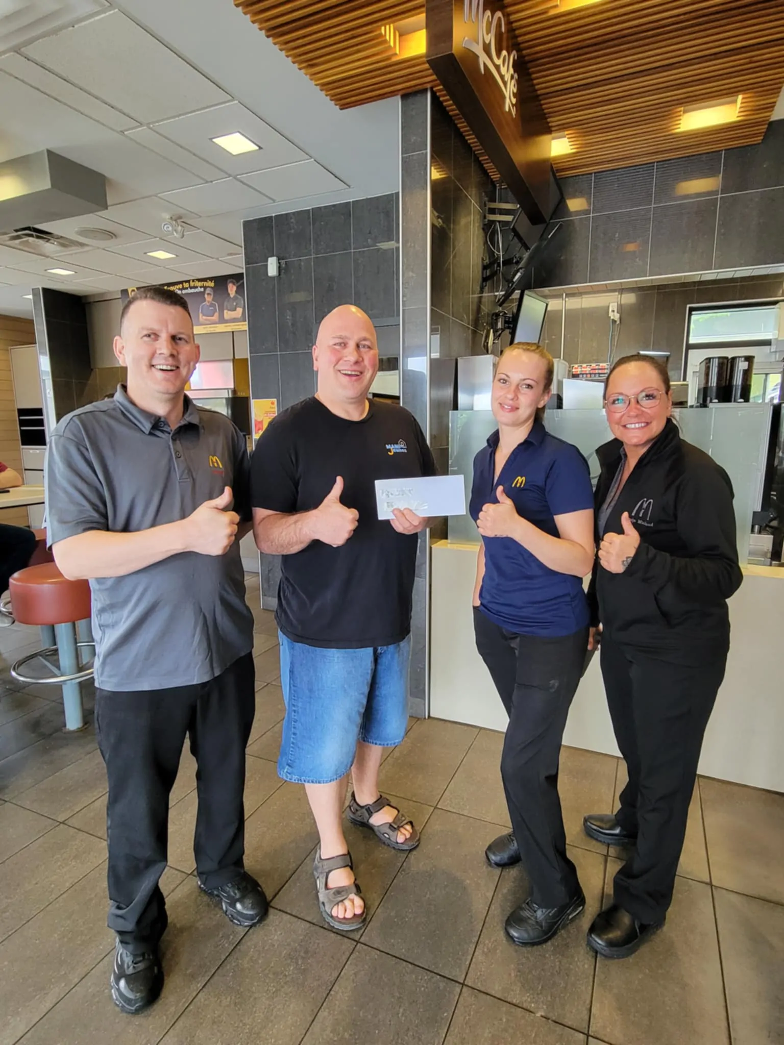 Quatre personnes devant comptoir du McDonald avec chèque dans les mains pour le Grand McDon de Maniwaki