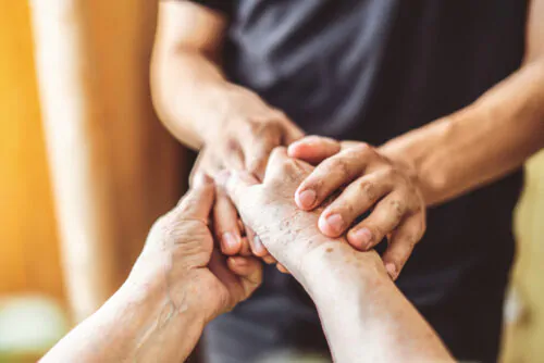 Une personne âgée tient les mains d'une personne plus jeune.