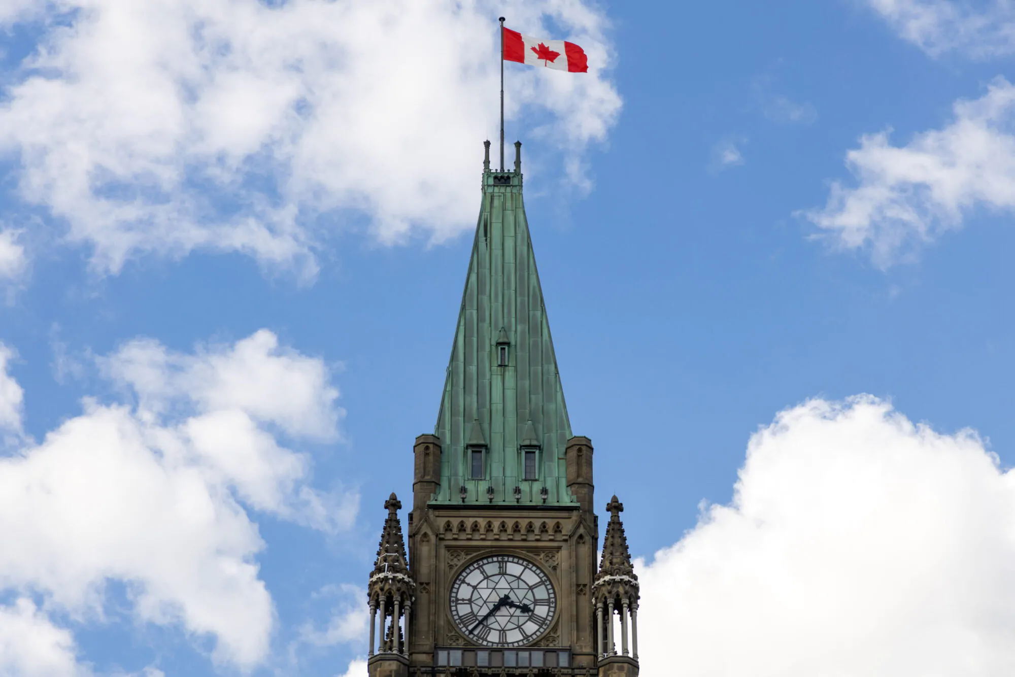 La tour d'un bâtiment du parlement canadien à Ottawa avec un drapeau sur fond de ciel bleu avec des nuages blancs.