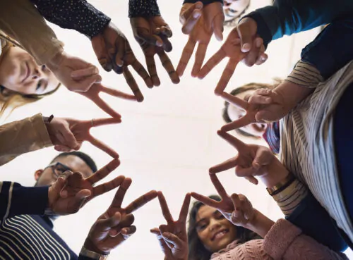 vue contre-plongée d'un groupe de jeunes de différentes origines regardant par terre et se touchant les mains