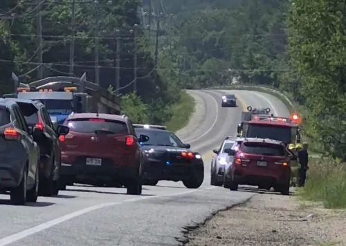 Des voitures sont à l'arrête sur une route, alors que des pompiers interviennent sur un accident et qu'une voiture de police est stationnée au milieu de la voie.
