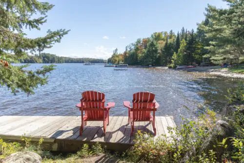 Des chaises de relaxation rouges sont posées sur un quai au bord d'un lac pendant la saison estivale.