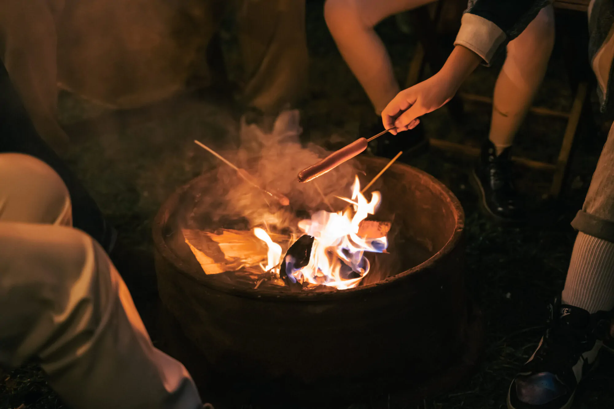 Family trailer travel. Children,brother sister,mom dad fry sausages on fire, eat hot dogs. Evening picnic in nature.Holiday barbecue BBQ food.Vacation weekend dinner.Road lunch.Camper,house on wheels
