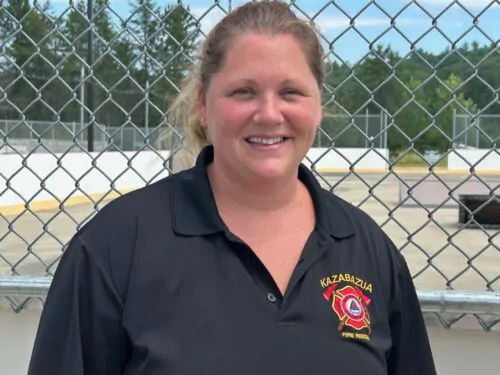 Jennifer Valcov, présidente, de l'Association des pompiers volontaires de Kazavazua, t-shirt noir avec logo, cheveux long blonds, queue de cheval, devant clôture du centre communautaire
