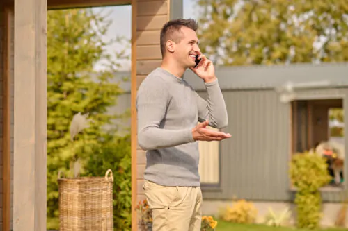 Un homme parle au téléphone à l'extérieur d'une maison en automne.