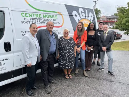 Un groupe de personnes prend la pose pour une photo devant un camion lettré aux couleurs de la Maison Amitié de la Haute-Gatineau.