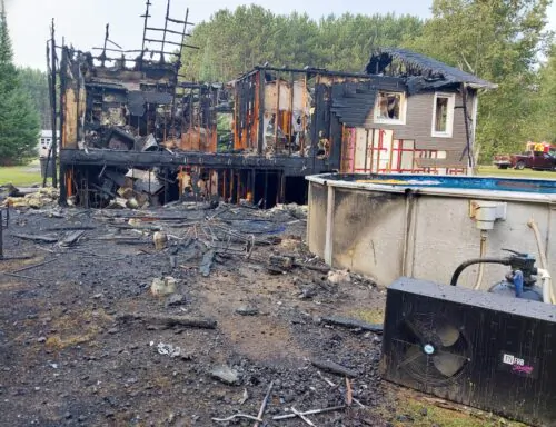 Les ruines d'une maison unifamiliale carbonisée par un incendie, avec une piscine au premier plan.