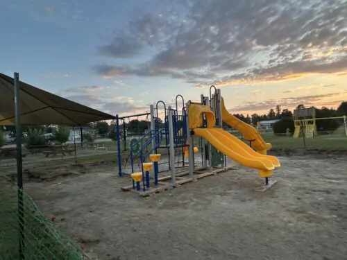 Module de jeu en installation au centre d'un parc, de couleur bleu et jaune pour les tout-petits dans un parc avec glissades