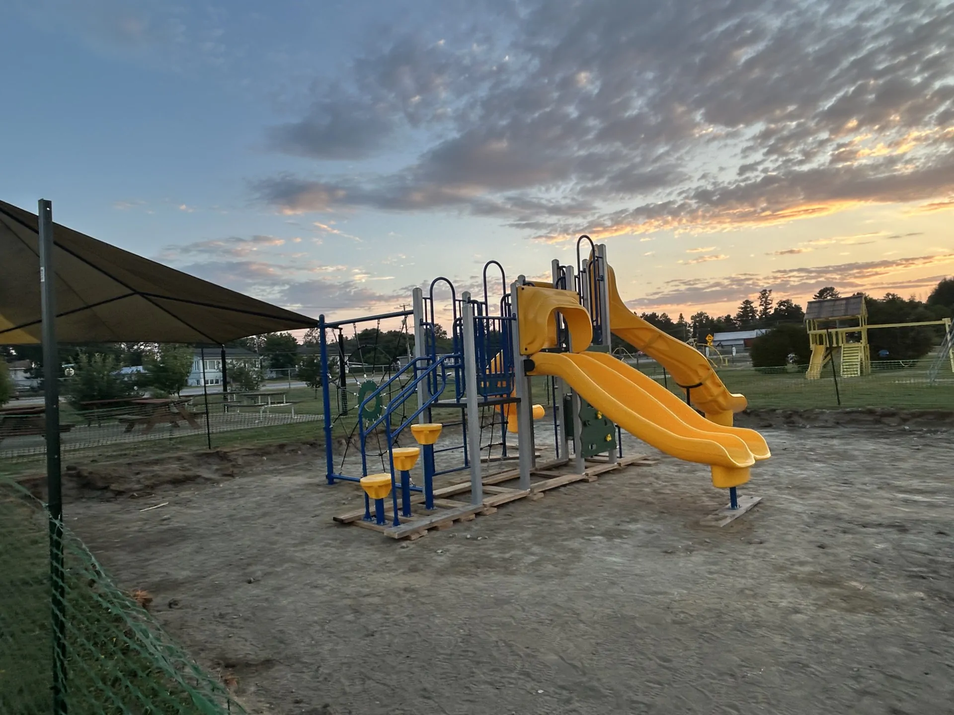 Module de jeu en installation au centre d'un parc, de couleur bleu et jaune pour les tout-petits dans un parc avec glissades