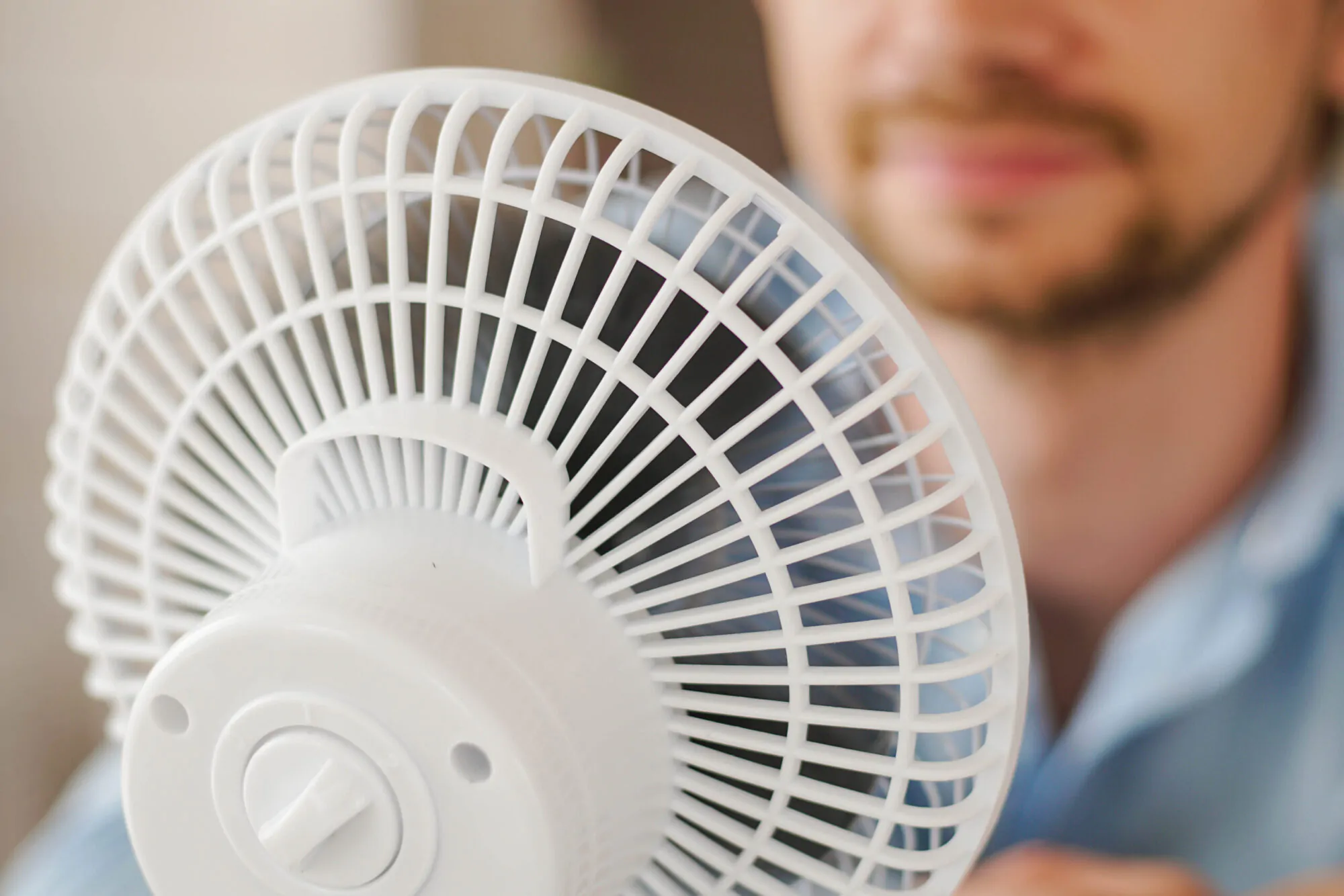 Un homme se rafraîchit avec un ventilateur pendant une chaude journée estivale.