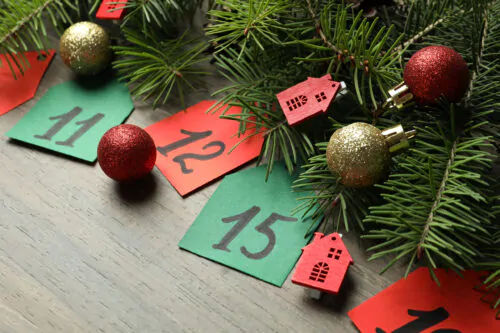 Calendrier de l'Avent sur fond de planche en bois et sapin avec décoration des Fêtes.