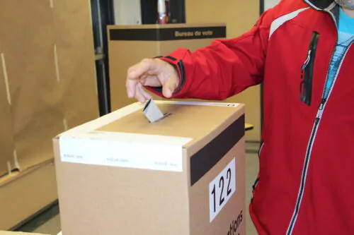Une personne dépose son bulletin de vote dans une urne.