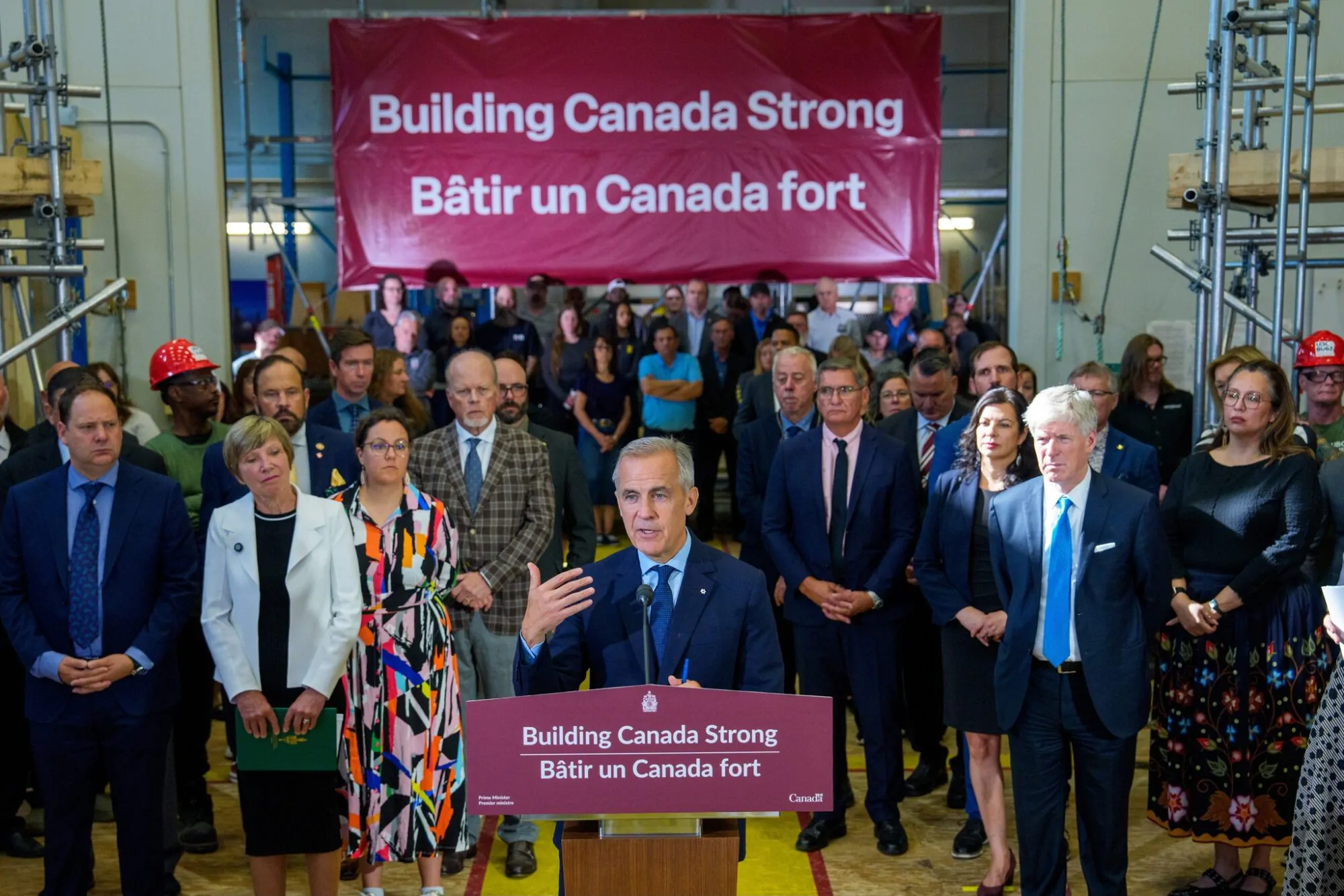 Le premier ministre du Canada, Mark Carney, livre un discours entouré d'une foule avec une grande banderole déployée sur laquelle est inscrite le slogan " Bâtir un Canada fort".